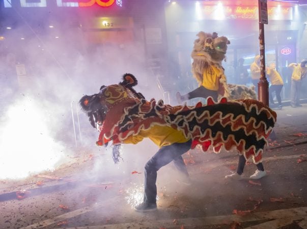 Lion dancers from the Philadelphia Suns perform in front of businesses on North 10th Street. (Jonathan Wilson for WHYY)