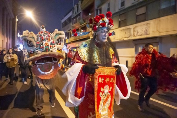 Lion dancers who are members of Cheung's Hung Gar Kung Fu Academy parade through Chinatown. In addition to teaching Kung Fu, the academy also teaches lion dance.  (Jonathan Wilson for WHYY)