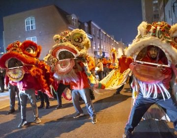 Lion dancers dance in the street during a parade.