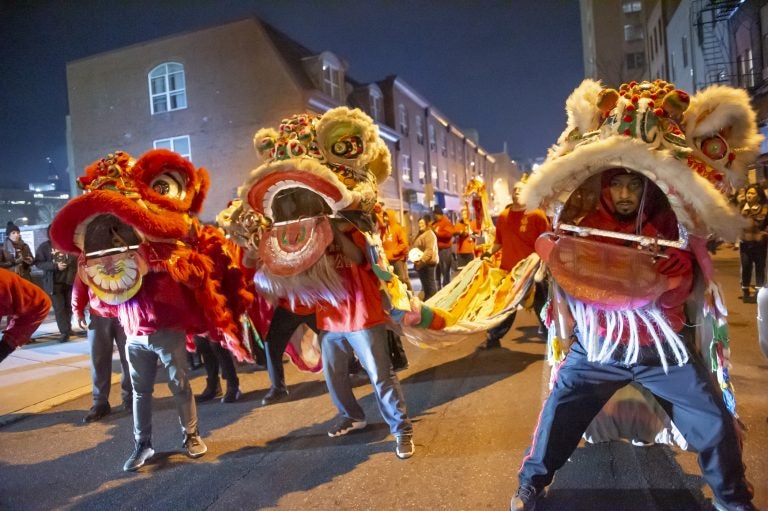 Lion dancers dance in the street during a parade.