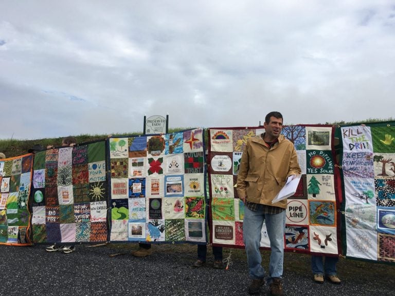 Mark Clatterbuck stands in front of a quilt designed to protest the Atlantic Sunrise pipeline. (Marie Cusick/StateImpact Pennsylvania)