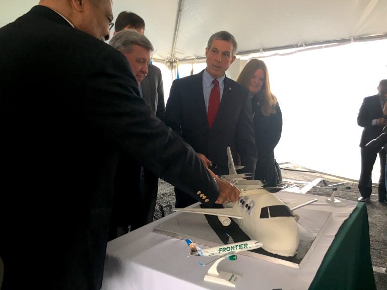 Instead of cutting a ribbon, Gov. John Carney joined leaders from the Delaware River and Bay Authority to cut a cake marking the return of commercial passenger flights to Delaware via Frontier Airlines. (Mark Eichmann/WHYY)