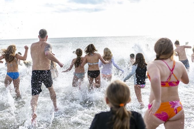 Participants of the 2020 polar bear plunge in Margate, NJ  run to the ocean on Wednesday, January 1, 2020. (Miguel Martinez for WHYY)