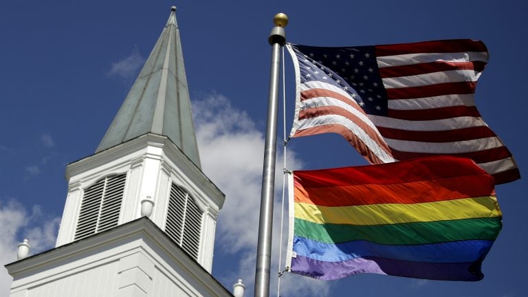 A rainbow gay pride flag flies below the U.S. flag last year in front of the Asbury United Methodist Church in Prairie Village, Kan. (Charlie Riedel/AP Photo)