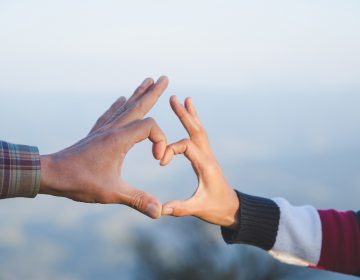 A couple makes a heart shape with their hands