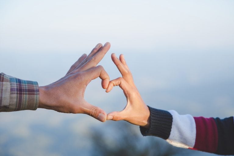 A couple makes a heart shape with their hands