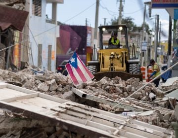 A Puerto Rican flag waves on top of a pile of rubble as debris is removed from a main road in Guánica. (Ricardo Arduengo/AFP via Getty Images)