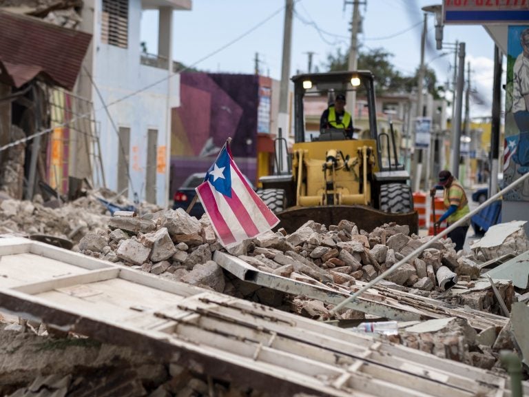 A Puerto Rican flag waves on top of a pile of rubble as debris is removed from a main road in Guánica. (Ricardo Arduengo/AFP via Getty Images)