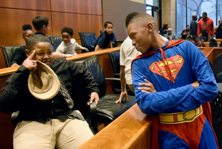 During a mock trial at Rutgers Law School, Superman, played by Nuri Waheed, banters with juror Corey Livingston-Randall, left, before the verdict is announced. (April Saul for WHYY)