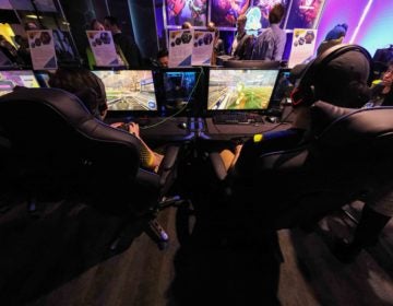 Two players are seen from behind their chairs at an esports arena