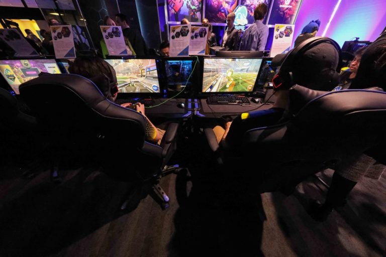 Two players are seen from behind their chairs at an esports arena