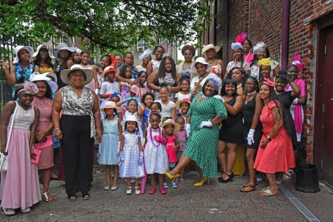 Tawanda Jones, in a green polka-dot dress, poses with attendees of a Mother-Daughter Tea at the Michael J. Doyle Fieldhouse gym in May 2019.  (April Saul for WHYY)