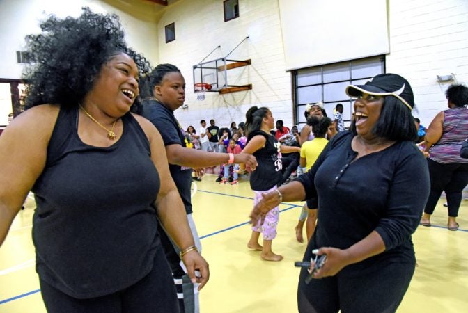 Tawanda Jones, right, and daughter LaQuicia Charnell, left; laugh at the Michael J. Doyle Fieldhouse gym during a sleepover sponsored by the Camden Sophisticated Sisters in June 2019.  (April Saul for WHYY)