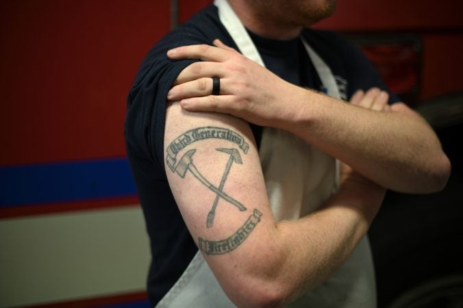 Thrid generation firefighter AJ Alves, 25, shows his tattoo as he poses for a photo at Humane Fire Co., in Pottsville, Pa. (Bas Slabbers for Keystone Crossroads)