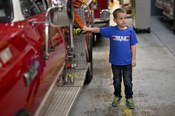 Tyler Donnatti, 6, son of the local fire chief, grandson of Gloria, stands next to the brush truck of Rainbow Hose Co., in Schuylkill Haven, Pa. (Bas Slabbers for Keystone Crossroads)