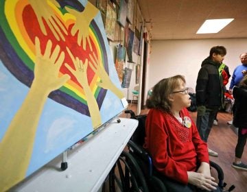 Artist Danielle Fangman is seen near her painting, 'Family Love,' during an art therapy exhibit on Feb. 10, 2020, at The Art Studio in Wilmington, Del. (Saquan Stimpson for WHYY)