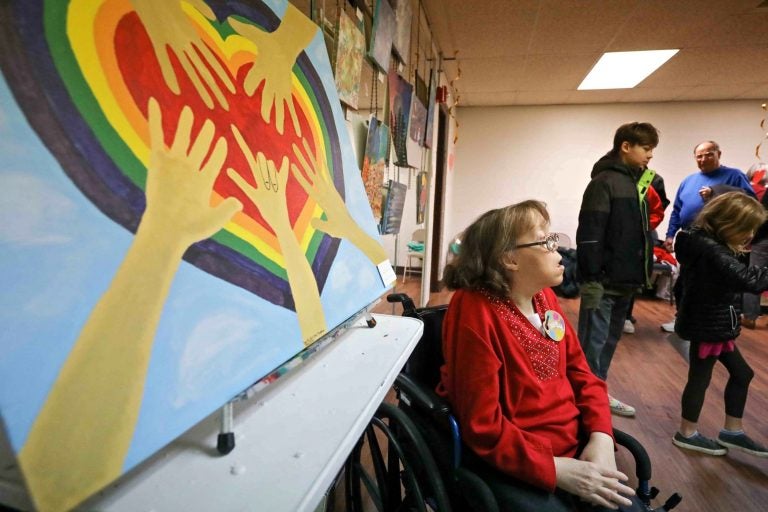 Artist Danielle Fangman is seen near her painting, 'Family Love,' during an art therapy exhibit on Feb. 10, 2020, at The Art Studio in Wilmington, Del. (Saquan Stimpson for WHYY)