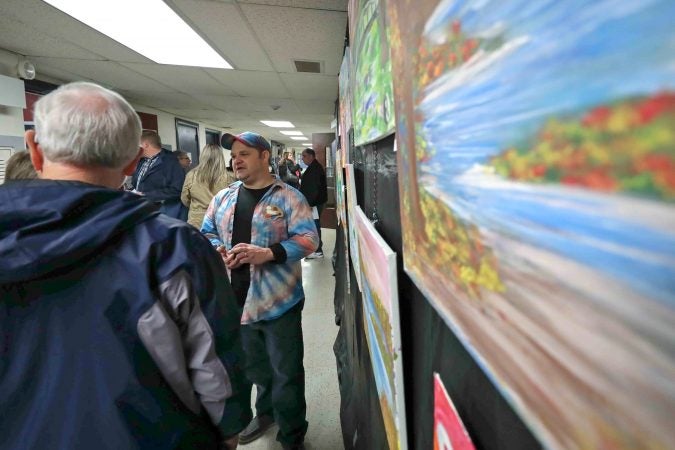 David Turner (center) speaks with attendees about his paintings during an art therapy exhibit on Feb. 10, 2020, at The Art Studio in Wilmington, Del. (Saquan Stimpson for WHYY)