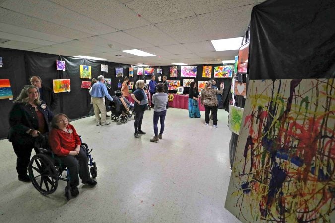 Attendees tour a gallery of paintings during an art therapy exhibit on Feb. 10, 2020, at The Art Studio in Wilmington, Del. (Saquan Stimpson for WHYY)