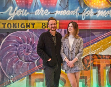 “Dispatches From Elsewhere” stars Eve Lindley (right) and Jason Segel (left) pose with local street artist Jimmy McMenamin's new mural at the Comcast Center. (Kimberly Paynter/WHYY)