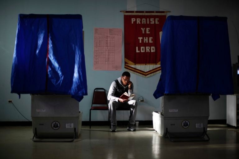 Election worker Khalid Battle reads a book as he waits for voters to cast their ballots in Pennsylvania primary election at Memorial Gospel Crusades Church in Philadelphia. (AP Photo/Matt Rourke)