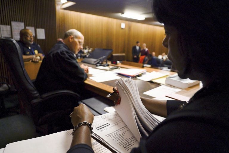 In this Aug. 30, 2017, photo, Stephanie Pope-Earley, right, sorts through defendant files scored with risk-assessment software for Jimmy Jackson Jr., a municipal court judge, on the first day of the software's use in Cleveland. In a growing number of local and state courts, including Cleveland, judges are now guided by computer algorithms before ruling whether criminal defendants can return to everyday life, or remain locked up awaiting trial. (Dake Kang/AP Photo)