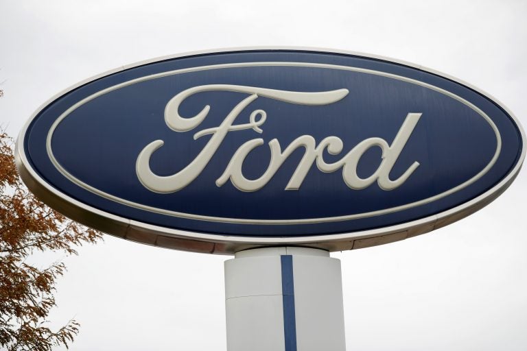 FILE - In this Oct. 20, 2019, file photo, the company logo stands over a long row of unsold vehicles at a Ford dealership in Littleton, Colo. (AP Photo/David Zalubowski, File)