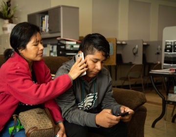 Fredy Garcia Morales and his mom Margarita talk to his sisters on the phone while sitting in the King Street Ministry Center in Chambersburg, Pa. (Jeffrey Stockbridge for Keystone Crossroads)
