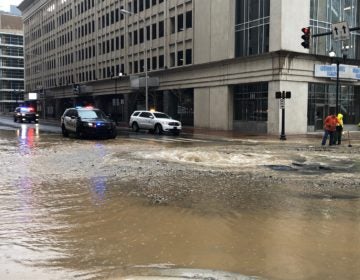 Public works crews were analyzing the water main break and city police blocked off access to the gusher. (Cris Barrish/WHYY News)