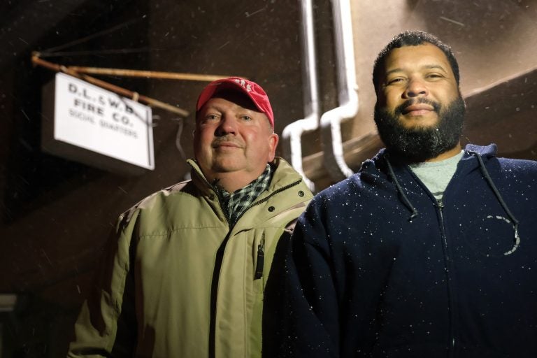 Andrew Barrow, left, and his brother Ronald Stanley Webb, Jr, nicknamed Stosh, right, stand outside Deer Lake and West Brunswick Fire Co. on Jan. 16, 2020, in Deer Lake, Pennsylvania. Webb was subjected to a racial slur while at Port Clinton Fire Company and his brother Barrow wrote an op-ed in the newspaper to bring attention to it. (Matt Smith for Keystone Crossroads)