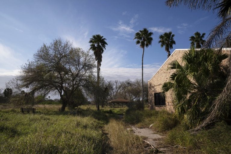 Grass and shrubs take over the closed Fort Brown Memorial Golf Course in Brownsville, Texas. The course was original built by the University of Texas system but the facilities are on the south side of the border wall. (Verónica G. Cárdenas for NPR)