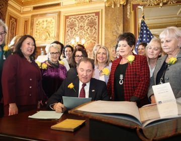 Utah Gov. Gary Herbert signs bill honoring the state's pioneering women suffragists on Wednesday. He's surrounded by state senators and representatives, and his wife, who are all wearing the yellow rose symbolizing suffrage. (Utah Governor's Office)