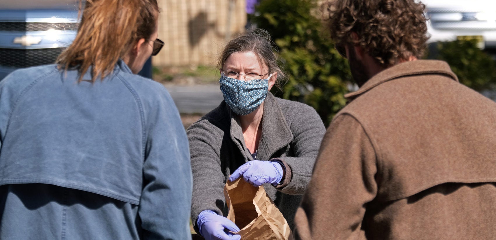 Jesse Tobin, from Primordia Mushroom Farm in Lenhartsville, wears gloves and a mask as she sells to customers Mar. 21, 2020, at the Easton Farmers' Market. Tobin says most of her family farm's business comes from selling to restaurants and that they've lost 80% of their revenue in just the last few days. (Matt Smith for Keystone Crossroads)