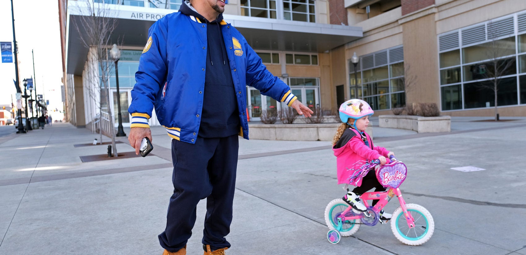 Edward Zayas, Jr., of Allentown, walks with his stepdaughter Avery Green, 4, as she rides her bike near the PPL Center in Allentown. Zayas is a chef at a bistro and has been working a lot to accommodate the increased demand for takeout and delivery orders. 