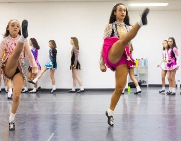 Dancers from the McDade-Cara School of Irish Dance warm up in their competition dresses for a dress rehearsal for the 2020 St. Patrick's Day Parade. (Emily Cohen for WHYY)