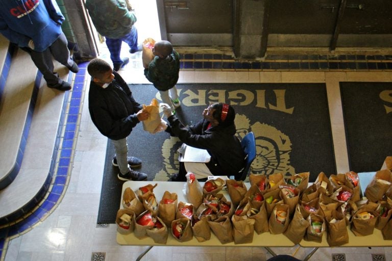 Daaiyah Boone hands out bagged meals to students at Tilden Middle School during the coronavirus shutdown. (Emma Lee/WHYY)