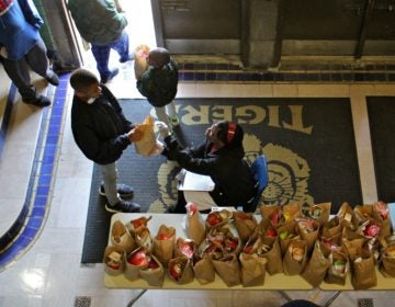 Daaiyah Boone hands out bagged meals to students at Tilden Middle School during the coronavirus shutdown. (Emma Lee/WHYY)