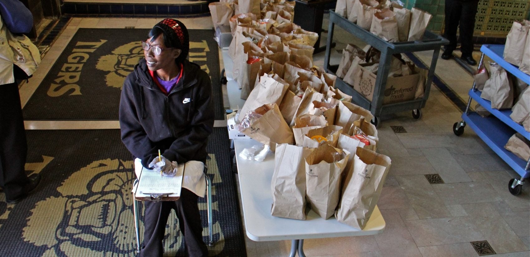 Daaiyah Boone waits near the door of Tilden Middle School in Southwest Philadelphia, ready to hand out bagged meals to students during the coronavirus shutdown. (Emma Lee/WHYY)