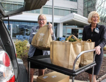 At Einstein Medical Center Montgomery, Chief Nursing Officer Annmarie Papa (left) and Chief Operating Officer Beth Duffy accept a donation of bagels and croissants from Four Worlds Bakery. (Emma Lee/WHYY)