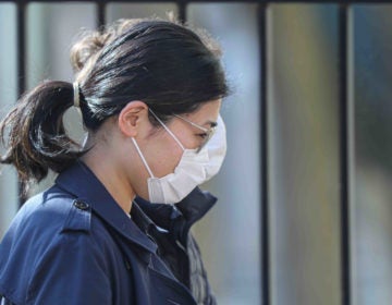 A woman walks in Wilmington, Del., wearing a protective mask