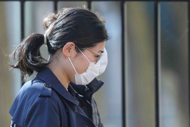 A woman walks in Wilmington, Del., wearing a protective mask