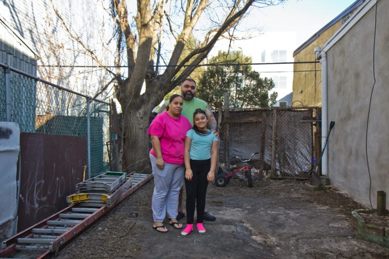 Adamarie Baez and Daniel Ortiz with their 10-year-old daughter Kaylee in the lot next to their home they’ve maintained and gardened in for years. (Kimberly Paynter/WHYY)