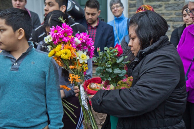 Carmela Apolonio Hernandez, a mother living in sanctuary at the Germantown Mennonite church, receives flowers from Suyapa Reyes. (Kimberly Paynter/WHYY)