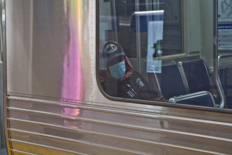 A subway rider in Philadelphia dons a surgical mask. (Kimberly Paynter/WHYY)