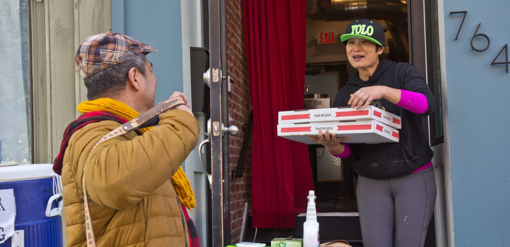 Kalaya owner Nok Suntaranon (right) hands out donated pizza to community members in need. (Kimberly Paynter/WHYY)