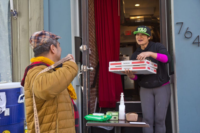 Kalaya owner Nok Suntaranon (right) hands out donated pizza to community members in need. (Kimberly Paynter/WHYY)
