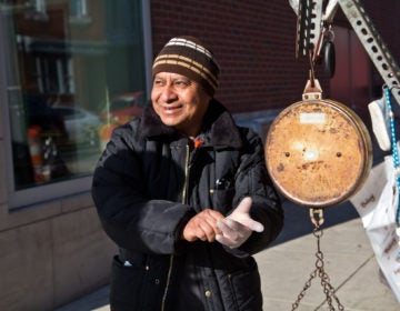 Magdaleno Corona puts on gloves at his fruit stand in South Philadelphia. (Kimberly Paynter/WHYY)