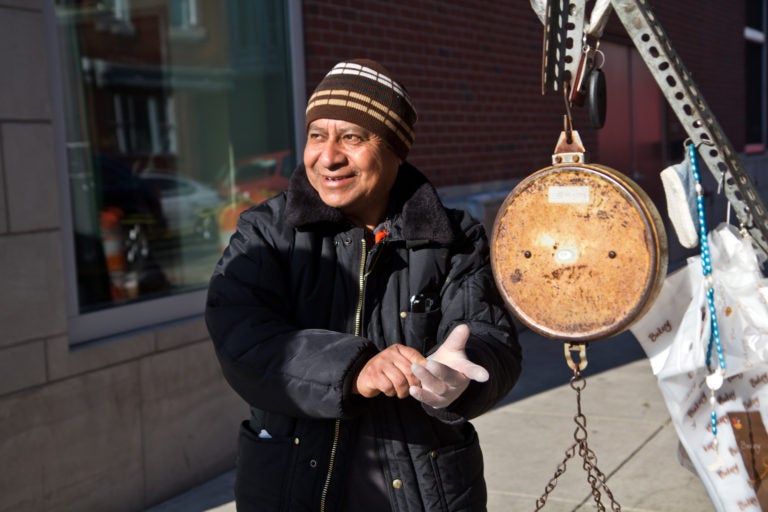 Magdaleno Corona puts on gloves at his fruit stand in South Philadelphia. (Kimberly Paynter/WHYY)