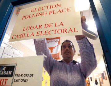 Dallas County election worker Maxx Nunez tapes up a sign before polls open for Super Tuesday voting at John H. Reagan Elementary School in the Oak Cliff section of Dallas, Tuesday, March 3, 2020. (AP Photo/LM Otero)