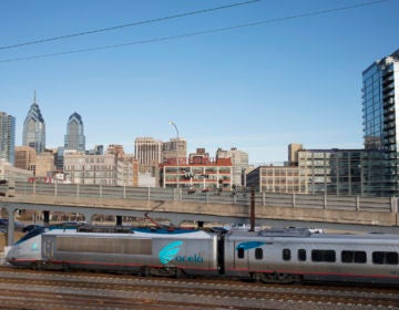 A train speeds by, as Philadelphia skyline is visible in the background.